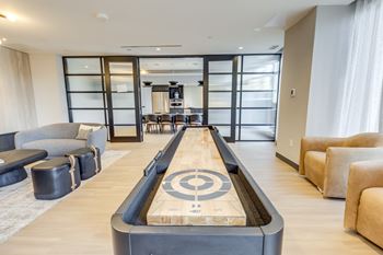 A shiny wooden air hockey table is in the middle of a living room.